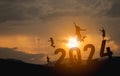 Woman jump happy new year 2024 concept, silhouette of woman jumping over barrier cliff and success with beautiful sunset Royalty Free Stock Photo