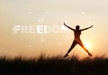 Woman jumping against sunset with word freedom