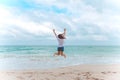 A woman jumping on the beach in front of the sea with feeling happy