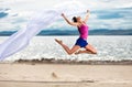 Woman jumping on the beach with a white tissue