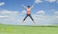 Woman jumping on green grass over blue sky Royalty Free Stock Photo
