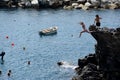 Woman jumping from high rock to sea in Manarola city