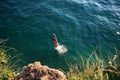 Woman jumping off cliff into the sea. Royalty Free Stock Photo