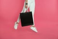 Woman jumping with paper shopping bag on color background.