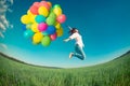 Woman jumping with toy balloons in spring field Royalty Free Stock Photo