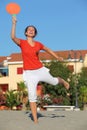 Woman jumps with tennis racket on beach