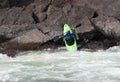 Woman on the kayak launching into the river from the rocks