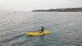 Woman on a kayak in a lutos postion meditating in the peaceful ocean. Drone view