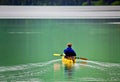 WOMAN ON KAYAK ROWING ON PEACEFUL LAKE