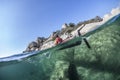 Woman kayaking on the sea along shores.