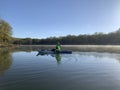 Woman kayaking on still waters with fog and sun glare