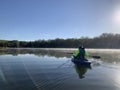 Woman kayaking on still waters with fog and sun glare