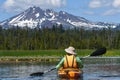 Woman kayaking toward snowy mountain peak