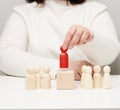 The woman keeps the red wooden figurine separate from the group. Career growth concept, unique person. Finding a talented employee