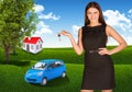 Woman with key in hand. Small automobile and house