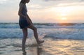 Woman kicking water at the beach during travel holidays vacation outdoors at ocean or nature sea at sunset time, Phuket, Thailand Royalty Free Stock Photo