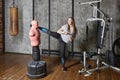 Punching bag bob dummy in gym, young woman kicks.