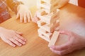 Woman and kid are playing jenga game. Trying to keep balance of tower from wooden blocks. Family leasure time. Concept Royalty Free Stock Photo