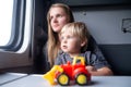 Woman with kid in a train compartment looks out the window. Family travel, holidays Royalty Free Stock Photo