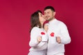 The woman kisses her beloved man on a red background. Young people holds white cups of tea Royalty Free Stock Photo