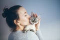 Woman Is Kissing And Cuddling Her Sweet And Cute Looking Devon Rex Cat. Kitten Feels Happy To Be With Its Owner. Kitty Sits In