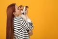 Woman kissing cute Jack Russell Terrier dog on orange background. Space for text Royalty Free Stock Photo