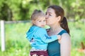 Woman kissing her two year old daughter in her arms, summer park Royalty Free Stock Photo