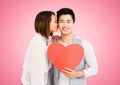 Woman kissing man while holding heart Royalty Free Stock Photo