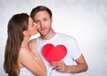 Woman kissing man while holding heart Royalty Free Stock Photo