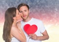Woman kissing while man holding a red heart Royalty Free Stock Photo