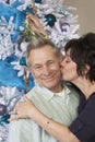 Woman Kissing Senior Man Under Mistletoe