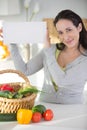 woman in kitchen with basket vegetables holding blank sign