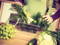 Woman in kitchen having vegetables holding shopping basket Royalty Free Stock Photo