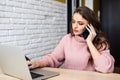 Woman in kitchen with laptop using cellular phone smiling at home Royalty Free Stock Photo