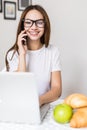 Young Woman in kitchen with laptop using cellular phone smiling in the morning Royalty Free Stock Photo