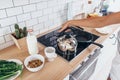 Woman in kitchen near stove holding kettle.