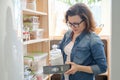 Woman in kitchen pantry. Storage wooden stand with kitchenware, products necessary to cook Royalty Free Stock Photo