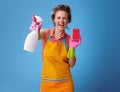 Woman with kitchen sponge showing bottle of detergent on blue Royalty Free Stock Photo