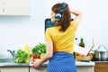 Woman in kitchen standing back. Girl cooking