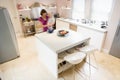 Woman in kitchen whisking on counter holding baby