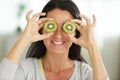 woman with kiwi slices in front eyes