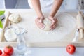 Woman kneading pizza dough on wooden pastry board