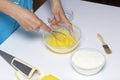 The woman kneads the dough in a glass container with chicken eggs and flour. Near the grater and brush.