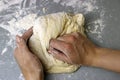 A woman kneads sweet yeast dough on the grey table