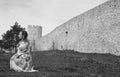 Woman kneeling next to an fortress wall and tower