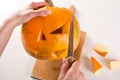 Woman with knife cuts pumpkin for Halloween holiday