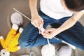 Woman knit with white thread knitting needles, sitting on beige plaid blanket. Hobby, crafting or handcraft. Casual clothes, jeans