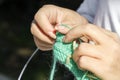 Woman knits clothes from wool with knitting needles.