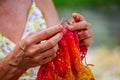 A woman knits a scarf with natural yarn