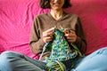 A woman knits from thick yarn